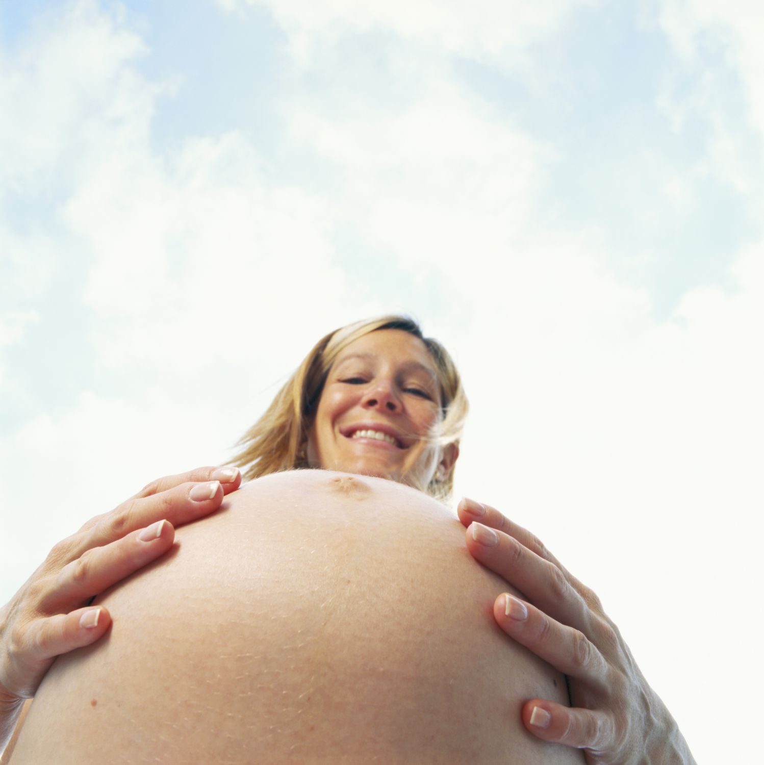 Eine schwangere Frau berührt ihren Bauch. Die Familienplanung ist in vollem Gange.